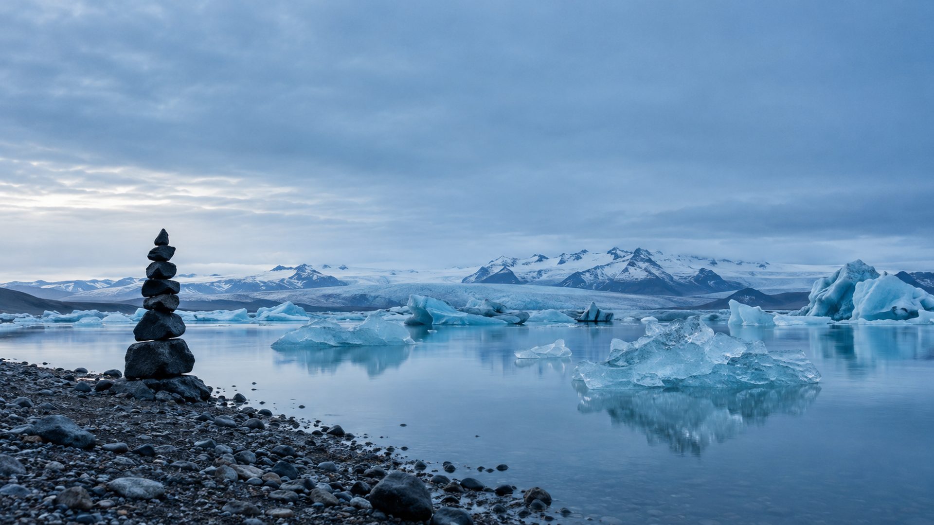 Translucent ice on a glacial lagoon with a stone cairn on the shore